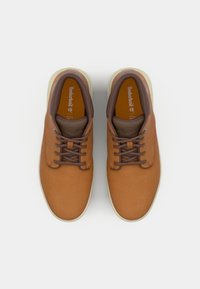 Zapatos de cuero marrón con un acabado suave, con cordones marrones, un collar acolchado y una suela de goma de color claro. Logo de Timberland en la lengüeta.