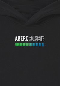 Sudadera negra con el texto "ABERCROMBIE" en blanco, con un patrón rectangular en degradado verde y azul debajo. Textura de tela suave.