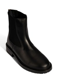 Schwarze Leder Chelsea-Boots mit elastischen seitlichen Einsätzen, flachem Absatz, runder Spitze und Zugschlaufe auf der Rückseite auf einem weißen Hintergrund.