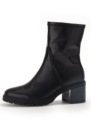 Schwarze Leder-Stiefeletten mit abgerundetem Zehenbereich, elastischem Seiteneinsatz und klobigem Absatz. Texturierte Gummisohle mit sichtbarem Profil.