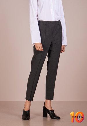 Szare, dopasowane spodnie o gładkiej fakturze z elastycznym pasem, w połączeniu z białą koszulą na guziki i czarnymi butami na wysokim obcasie.