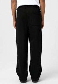 Zwarte joggingsbroek met een losse fit, gemaakt van zacht materiaal, voorzien van een achterzak en een elastische tailleband voor comfort.