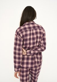 Plum and blush pink plaid flannel shirt features a collar, long sleeves, and button cuffs. The back has a straight hem and side slits.