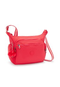 Rød nylon crossbody-taske med en glat overflade, der har en frontlomme med lynlås, et logo-patch og en fluffy charm hængende fra lynlåstrækkeren.
