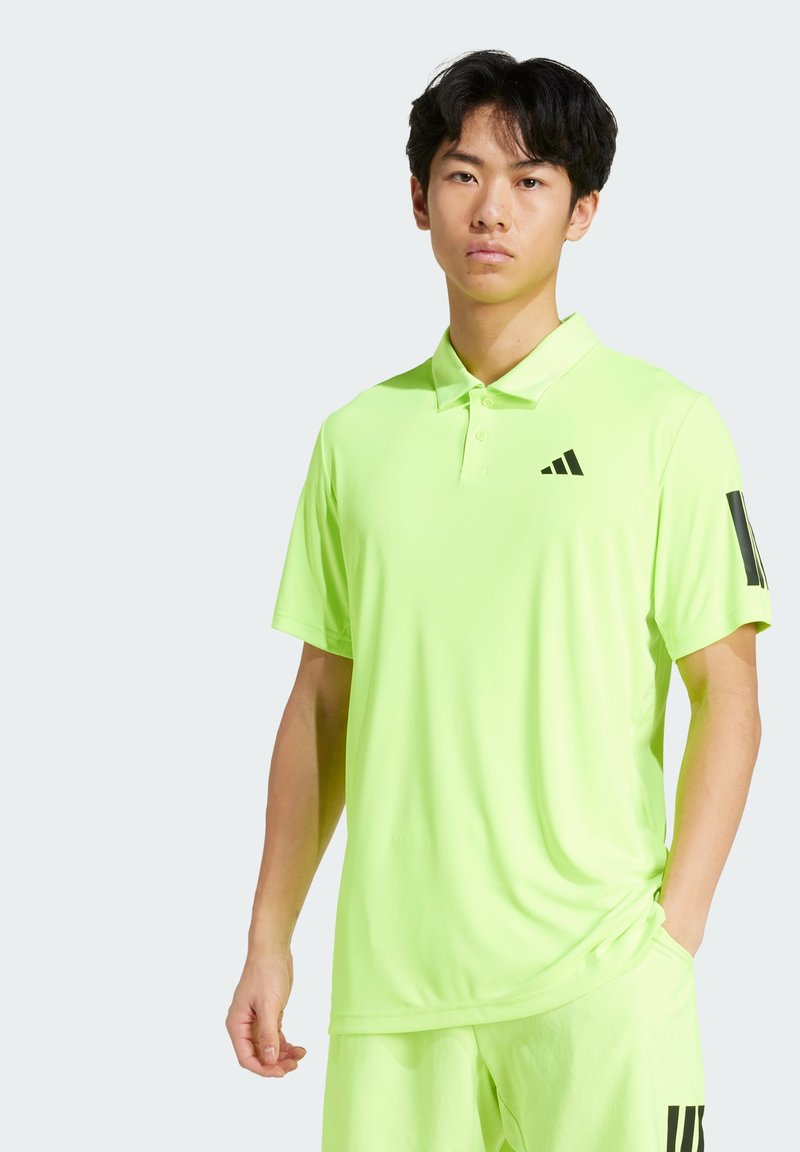 Világos zöld pólóing klasszikus gallérral, rövid ujjakkal, háromgombos felsőrészen és fekete adidas logo-val a mellkasán és az ujján.
