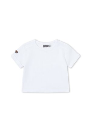 Camiseta blanca lisa de manga corta para niño pequeño, con cuello redondo, un pequeño parche marrón en la manga izquierda y una etiqueta dentro del cuello que dice "CANADA".