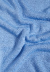 Ljusblått stickat tyg med en jämn textur, som har krusningar och vecken, vilket visar mjuka fibrer och ett konsekvent mönster.