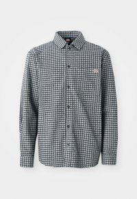 Zwart-wit geblokte blouse met lange mouwen, kraag, en een klein logo-patch op de linker borstzak.