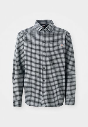 Long-sleeve black and white checkered button-up shirt with collar and small logo patch on the left chest pocket.