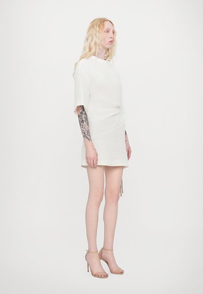 Short white linen dress with short sleeves and a knot detail at the waist, paired with nude strappy high heels. Smooth texture, minimalist design.