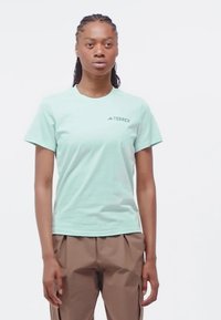 Vihreä mintunvärinen t-paita lyhyillä hihoilla, jossa on pyöreä kaula-aukko ja "Terrex"-logo vasemmassa rinnassa. Valmistettu sileästä, kevyestä kankaasta.