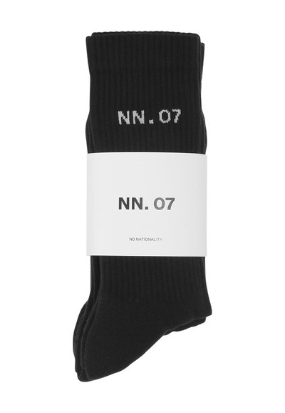 Calze nere a coste con logo bianco "NN. 07". Imballate con un'etichetta bianca con la scritta "NO NATIONALITY". Texture morbida, design classico delle calze.