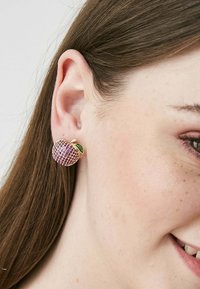 Orecchini a forma di mela in tono dorato, decorati con strass rosa e un accento di foglia verde. Texture liscia, design compatto, adatti per un look casual.