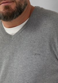 Grijze v-hals trui van gebreid materiaal. Heeft een subtiele geborduurde logo, geribde halslijn en een gladde textuur.