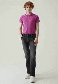 Rosa kortermet polo med knappestolpe, kombinert med mørk denim jeans og hvite joggesko. Enkel og tett passform.