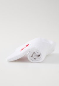 Witte katoenen handdoek opgerold, met een klein rood geborduurd ontwerp. Zachte textuur met een fijne, absorberende weving.