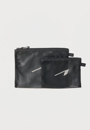 To sorte netstofpunge med lynlås, den ene større og den anden mindre, lagt fladt på en hvid overflade med en lille træksløjfe på hver.