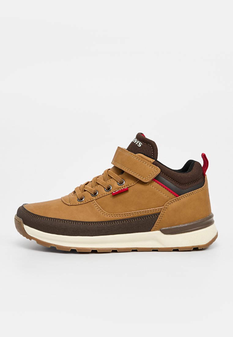 Zapato de cuero sintético marrón con una suela de goma, diseño de cordones, correa de Velcro y acentos rojos. Presenta un cuello acolchado y detalles texturizados.