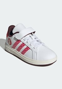 Białe skórzane sneakersy z różowymi perforowanymi paskami, szarymi sznurowadłami i rzepem. Guma podeszwy i mały emblemat po boku.