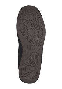 Schwarze Gummisohle mit einem strukturierten Muster, das Rillen und kreisförmige Designs für besseren Halt aufweist. Die Seitenkanten sind leicht erhoben.