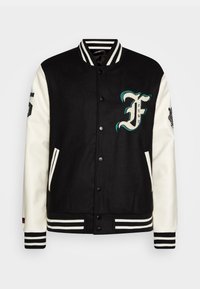 Black varsity jacket with white leather sleeves, striped ribbed collar and cuffs, featuring embroidered “F” logo and side pockets.
