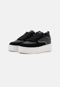 Sneaker neri con un mix di suede e ecopelle, dotati di una suola bianca spessa, punta rotonda e dettagli di cucitura intricati.