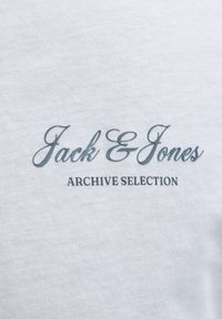 Jack & Jones Archive Selection tekst i kursiv og blokbogstaver trykt på hvidt stof.