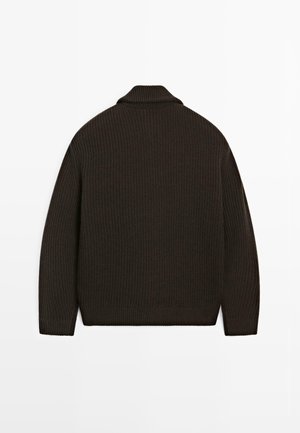 Kraftig mørkebrun strikket sweater med høj krave, ribbet tekstur og lange ærmer. Har en afslappet pasform og en kant med bølger.
