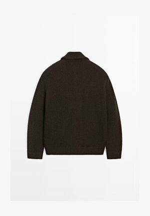 Kraftig mørkebrun strikket sweater med høj krave, ribbet tekstur og lange ærmer. Har en afslappet pasform og en kant med bølger.