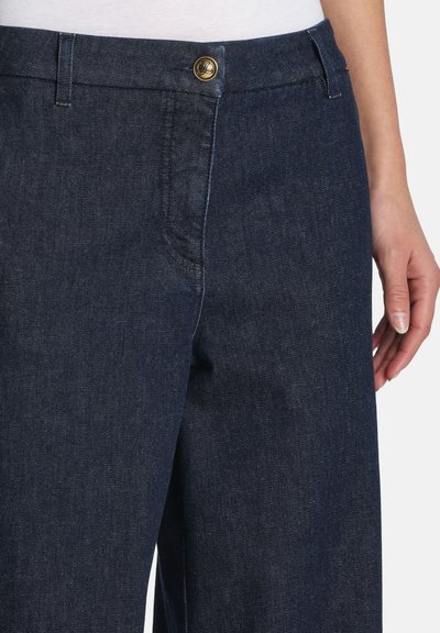 Mørkeblå denimbukser med lige snit, frontknaplukning med guldfarvet detalje og en glat tekstur.