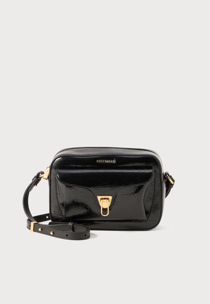 Black patent leather crossbody bag with gold hardware, zip closure, front pocket, and adjustable strap. Smooth texture with minimalist design.
