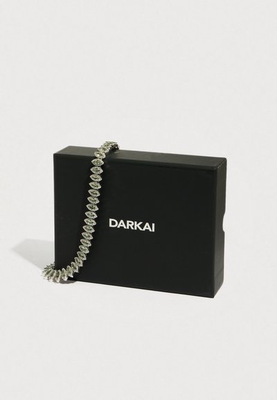 Hõbedatooni käevõru, millel on marquise-lõikega kivid lehekujulise mustrina, asetatud mustale karbile, millel on silt "DARKAI".