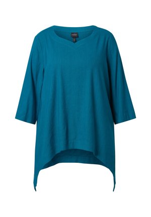 Sininvihreä pellavainen tunika, jossa on kolmen neljänneksen hihat, V-aukko ja epäsymmetrinen helma, joka on pidempi sivuilta kuin edestä ja takaa.