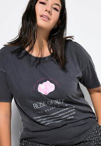 Zwart katoenen graphic t-shirt met een roze kwarts illustratie en tekst over liefde, genezing en medemenselijkheid. Korte mouwen en ronde hals.