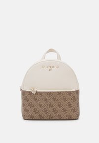 Sac à dos avec un dessus crème et une partie inférieure à motifs marron. Il est équipé d'un matériel doré et d'une fermeture éclair avant ornée d'un bijou en forme de cœur.