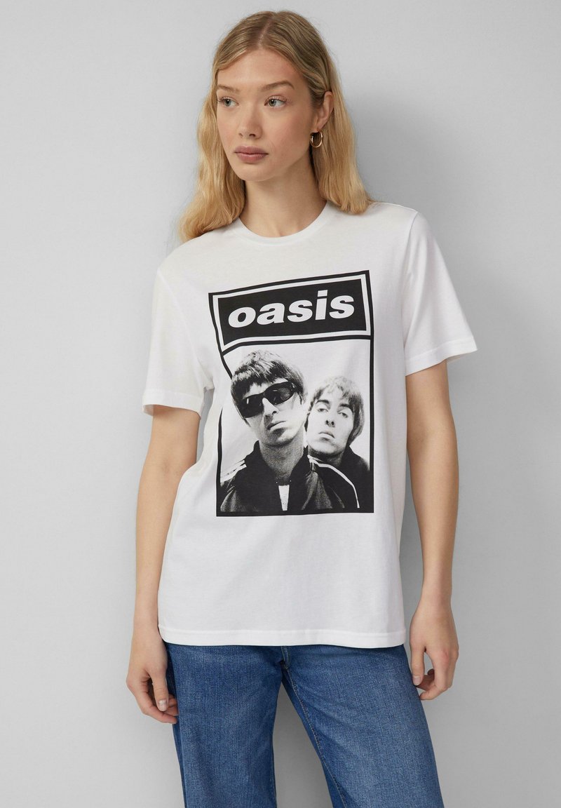 Witte katoenen T-shirt met een zwart-wit grafische print van twee muzikanten en de tekst "oasis" in een vet, rechthoekig logo.