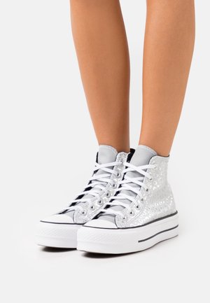 Baskets montantes avec un dessus en argent texturé brillant, une semelle en caoutchouc blanc, des accents noirs et des lacets blancs.