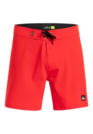 Rode zwemb trunks gemaakt van gladde stof, met een zwarte trekkoord, een voorkantseins en een klein logopatch aan de onderlinkerkant.