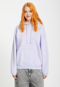 Lavendel hoodie met een voorzak, een trekkoord en geribbelde manchetten. Gemaakt van zacht materiaal, met een relaxte pasvorm en subtiele branding.