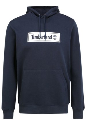Granatowa bluza z kapturem z kangurzymi kieszeniami z przodu, kaptur ze ściągaczem oraz białe, prostokątne logo Timberland na piersi.