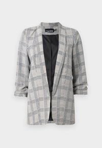 Checkered blazer in black and white with an open front, wide lapels, and rolled sleeves. Made of smooth fabric with a contrasting black lining.