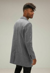 Abrigo de mezcla de lana gris con un diseño ajustado, solapa con muesca y tres botones negros en cada manga. Presenta una silueta estilizada.