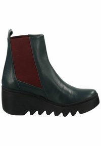 Bottes de cheville en cuir vert avec des panneaux latéraux élastiques bourgogne, bout arrondi et semelle épaisse en wedge noire avec un motif à biseaux.