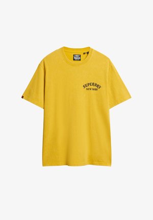 T-shirt di cotone giallo, vestibilità oversize, con logo nero "Superdry New York" sul lato sinistro del petto, scollo rotondo, maniche corte.