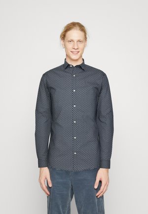 Langärmliges Hemd in Marineblau mit geometrischem Muster, geknöpftem Kragen und Manschetten, aus leichtem Stoff, kombiniert mit hellblauen Cordhosen.