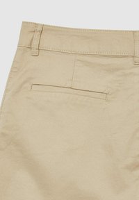 Pantaloni in cotone beige con vita standard, tasca posteriore e texture liscia con dettagli di cucitura discreti.