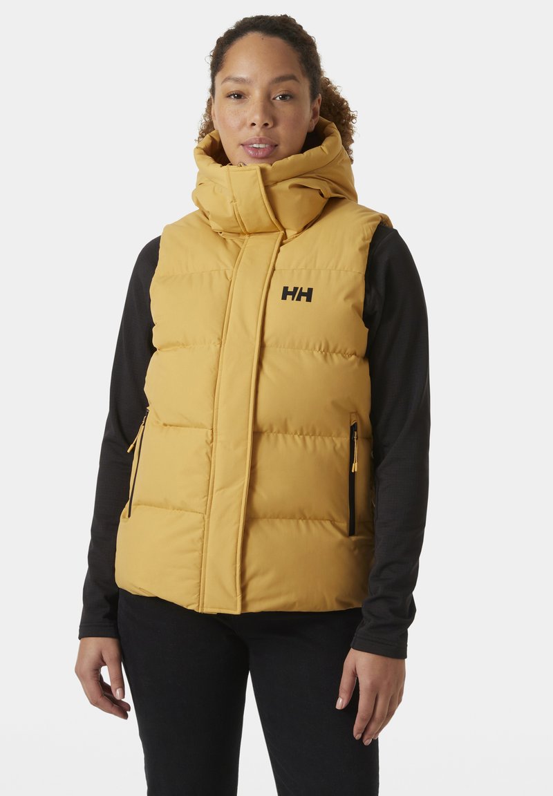 Gelbe Pufferweste mit hohem Kragen, seitlichen Reißverschlusstaschen und schwarzem Logo. Sie hat ein gestepptes Design mit einer glatten Textur.
