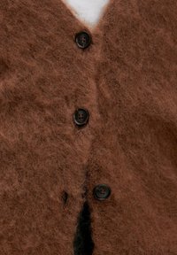 Bruine fuzzy cardigan met een zachte textuur, voorzien van zwarte knopen en een v-hals ontwerp. Opvallend fleecemateriaal detail verbetert het uiterlijk.