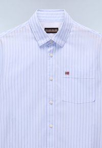 Chemise à rayures bleu clair avec boutons, fabriquée en tissu lisse, comportant une poche poitrine et un petit accent avec le drapeau norvégien.