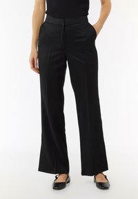 Zwarte broek met wijde pijpen, een zachte textuur, voorpanden en zijzakken. G gecombineerd met zwarte flats voor een strakke uitstraling.